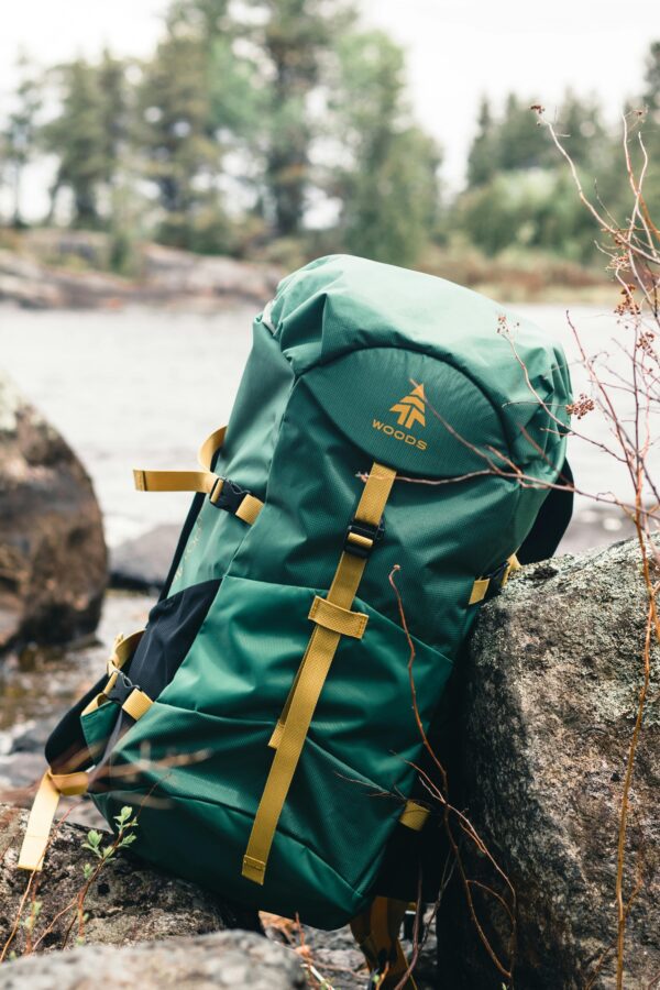 A green backpack rests on rocks in a scenic Canadian wilderness setting, perfect for outdoor enthusiasts.