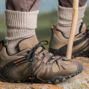 Hiking boots by Merrell on a rock edge, featuring outdoor adventure gear.